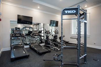a gym with cardio equipment and a tv